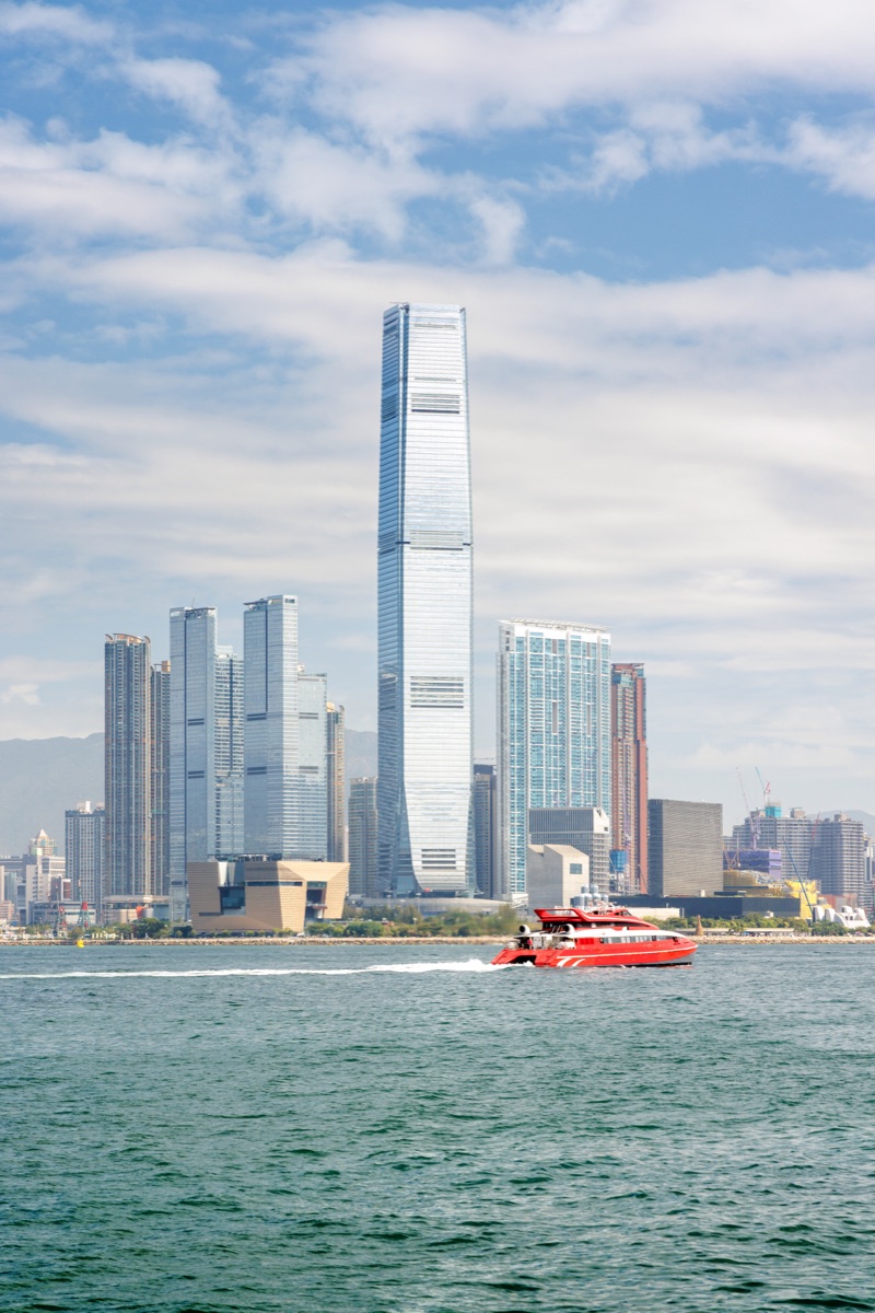 Hong Kong skyscraper panorama on a sunny day with water and boats, bright urban seascape