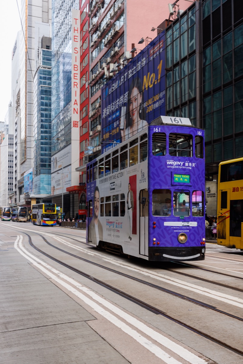Classic double decker trams running along busy streets of Hong Kong, one of the city iconic public transport systems