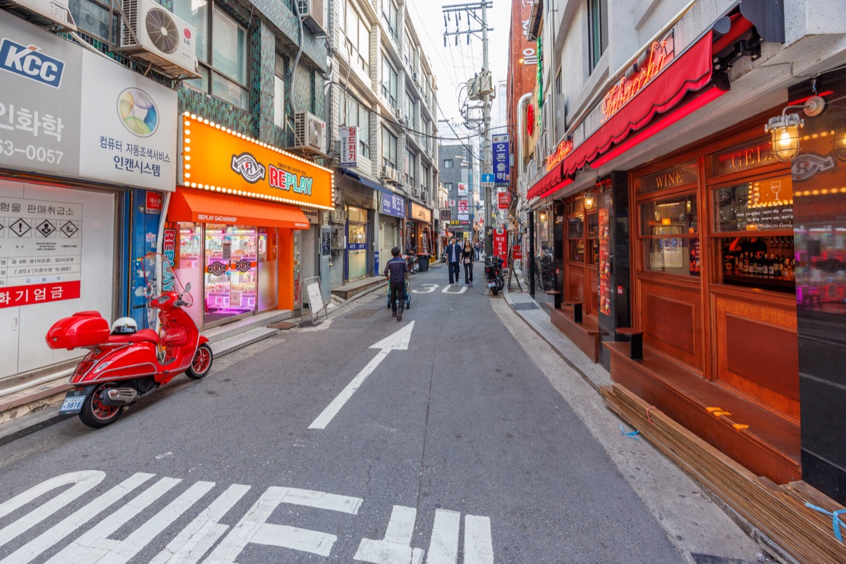 Pedestrians walk along a commercial street lined with shops, restaurants and retail businesses in the Myeongdong district of Seoul