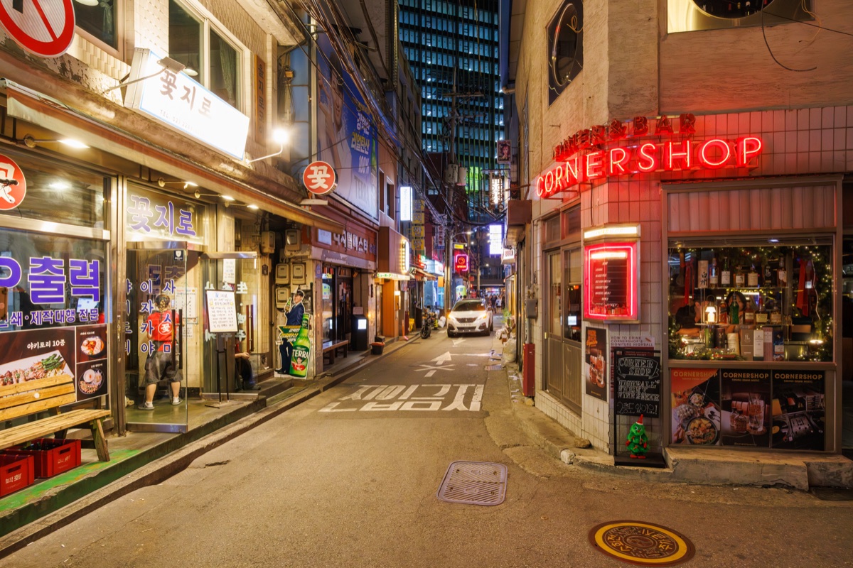 Restaurants, bars and illuminated storefronts along a narrow street in downtown Seoul