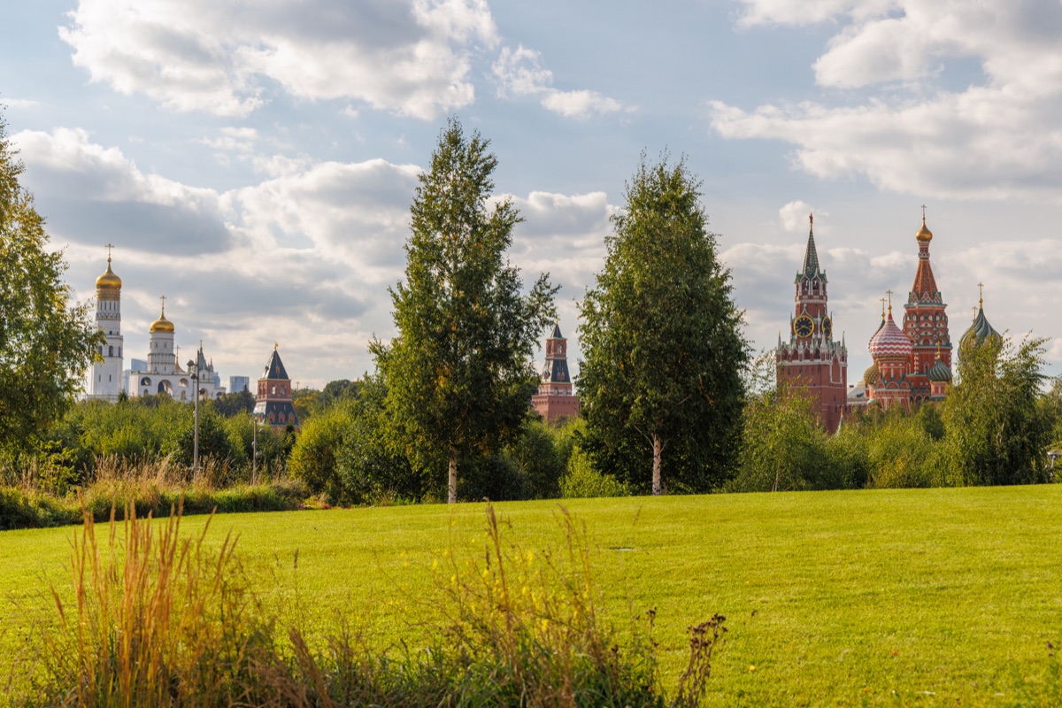 Birch trees and a broad green lawn frame a view of the Kremlin towers and Saint Basil's Cathedral from Zaryadye Park.
