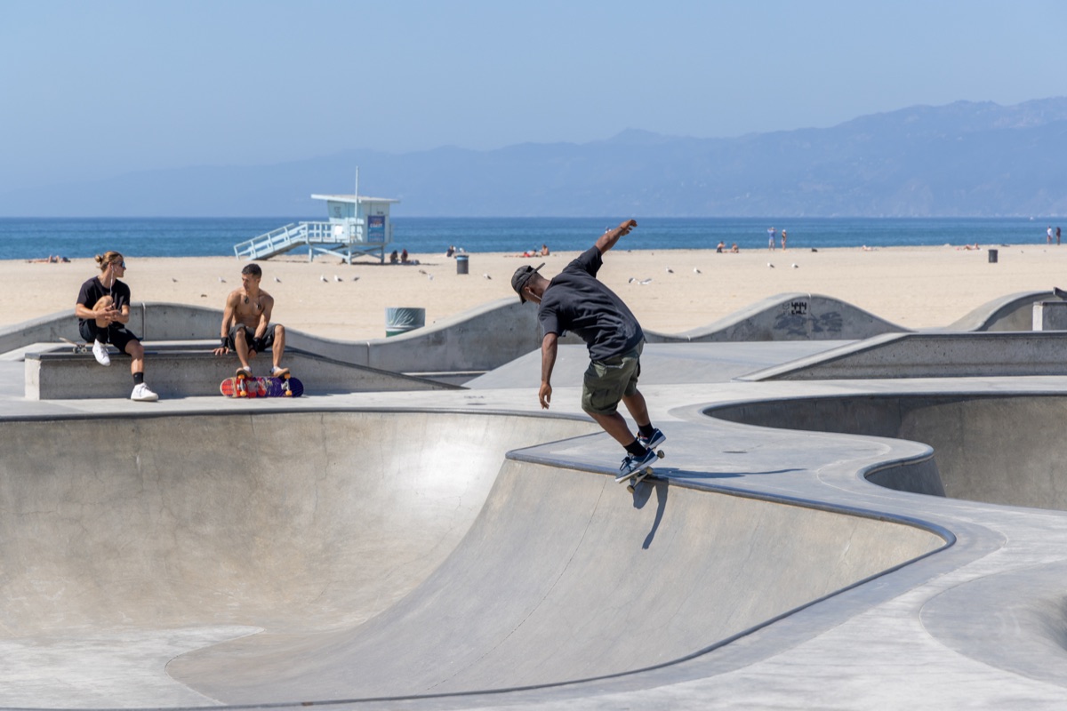 Skaters riding and practicing tricks at the skate park in the Venice Beach area, showing active youth culture and urban lifestyle.